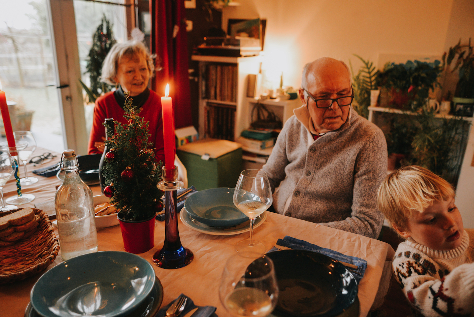 Weihnachtsrituale: Die Großeltern sitzen am Tisch und beobachten ihr Enkelkind.
