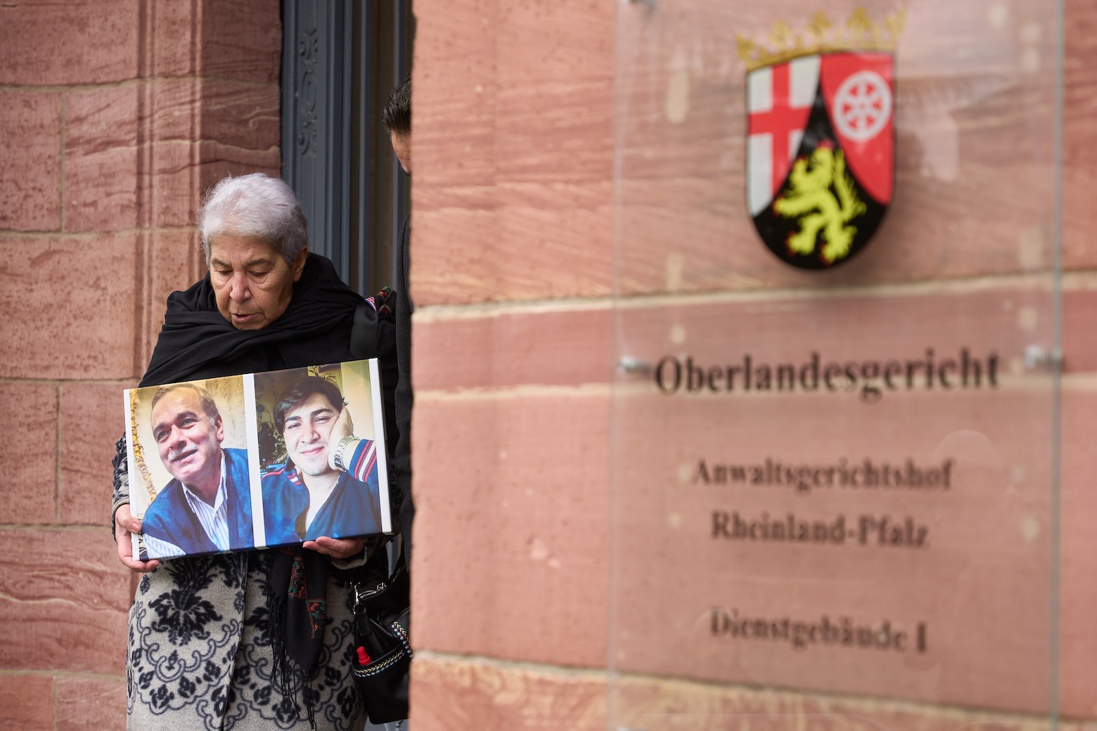 Eine Syrerin zeigt Bilder ihrer verschwundenen Angehörigen vor dem Oberlandesgericht Koblenz.